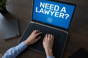 Individual typing on a computer "Need a Lawyer"